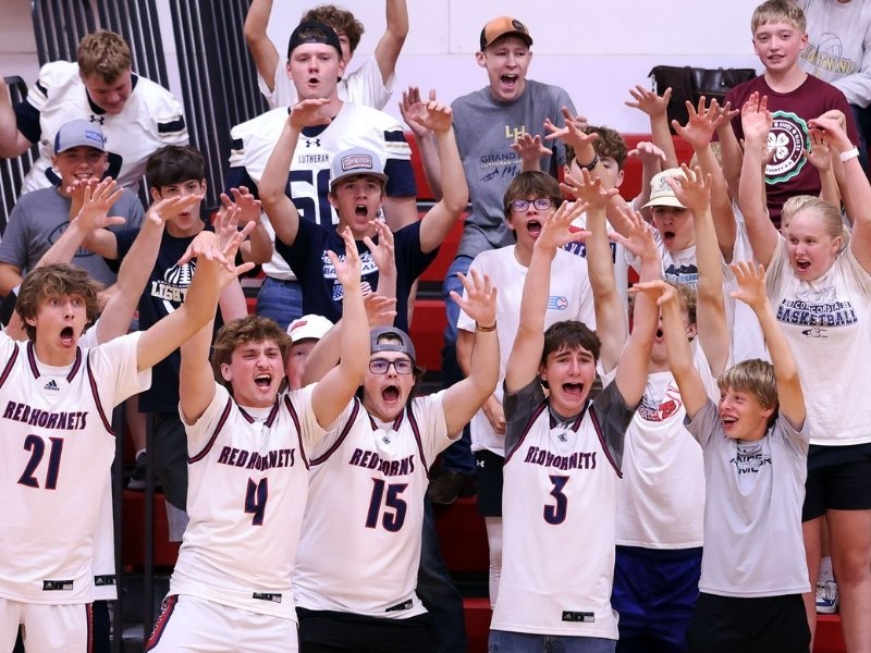 Students cheering from the stands in the gym during volleyball. 