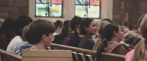 Students sitting filling church pews.