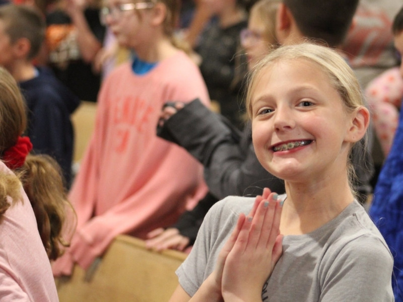 Elementary girl with a big smile in church as she is praying. 